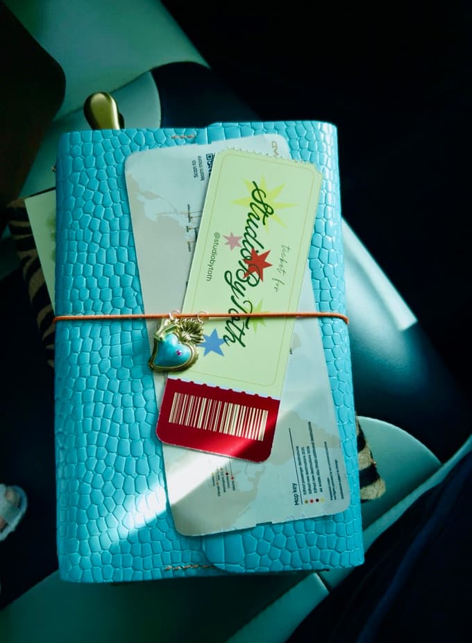 A turquoise croc-embossed leather journal with a heart charm and a tag
